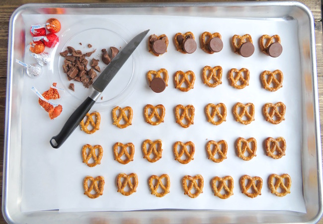 Placing Hershey Kisses face down in pretzels