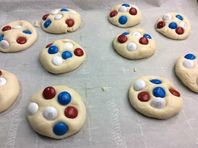 Adding M&M's to sugar cookies.
